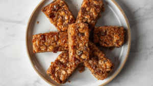 Homemade date bars with nuts and oats on a rustic table, surrounded by scattered nuts and dates.