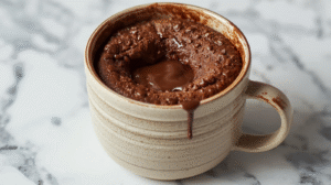 A delicious Nutella mug cake in a white mug, topped with Nutella.